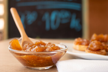 Glass pot with a delicious homemade apple and onion chutney, with cinnamon on a light wooden board. Perfect jam for breakfast. Breakfast, cooking, food concept.