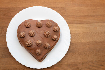 Heart-shaped cake base on a white plate. Wooden background.