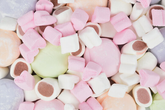 Top view of different types of marshmallows in a mess spread out on a table surface