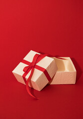 White gift box with red ribbon on red background. Concept of Valentins Day, copy space and mock up