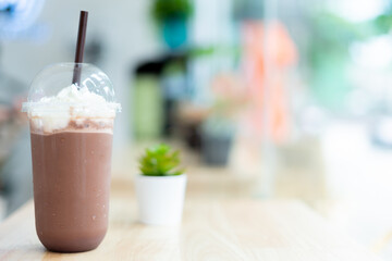 Iced cocoa drink with whipped cream served in plastic cup. With the background in the coffee and beverage shop