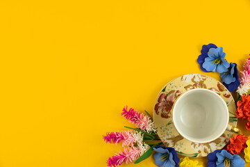 Cozy concept, yellow isolated background, tea party set with flowers, top view and copy space, border