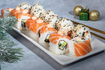 Sushi Sets Uramaki, California, Philadelphia, on a white plate. New Year and festive concept. On a light gray background.