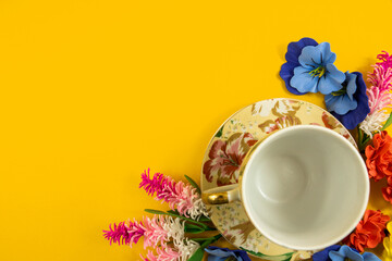 Cozy design, tea set and decorative flowers on a yellow background, copy space, top view, flat lay at border