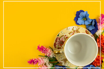 Cozy design, tea set and decorative flowers on a yellow background, copy space, top view, flat lay with white border