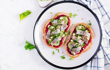 Herring fillet. Sandwich with salted herring and beetroot pate on the  toasts on white plate. Scandinavian cuisine. Top view, overhead