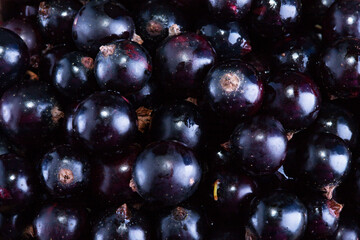 Black currant and green leaves on a dark wooden background. Background with currant berries and green leaves. Currant Macro.