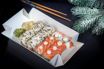 Sushi Sets Uramaki, California, Philadelphia, on a white plate. Festive, New Year concept. Against a dark reflective background.