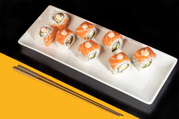 Sushi Sets Uramaki, California, Philadelphia, on a white plate. Festive, New Year concept. Against a dark reflective background.