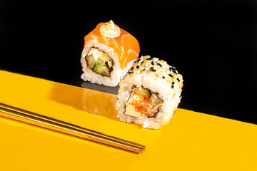 Sushi Sets Uramaki, California, Philadelphia, on a white plate. Festive, New Year concept. Against a dark reflective background.