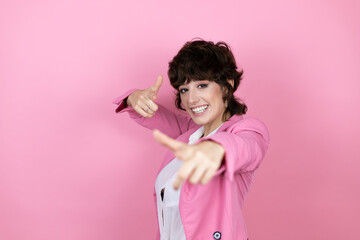Young business woman over isolated pink background pointing to you and the camera with fingers, smiling positive and cheerful