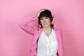 Young business woman over isolated pink background putting one hand on her head smiling like she...