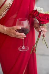 bridesmaid in red sari holding a wine glass with red wine