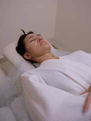 a girl in a white coat is lying with her eyes closed in a massage room. 