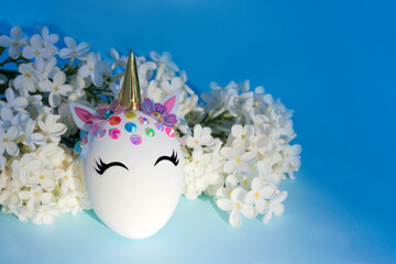 Creative decorative Easter egg in the form of a unicorn with white delicate flowers around