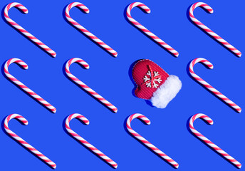Christmas seamless pattern. Candy canes and Santa's red mitten on bright blue background.