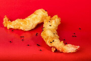 King prawns in batter, sprinkled with sesame seeds. Festive dinner. Healthy eating. On a red background.