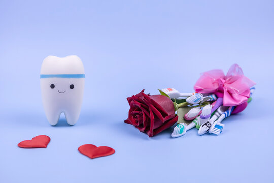 toy model of a tooth, a bouquet of toothbrushes, a red rose and hearts on a blue background