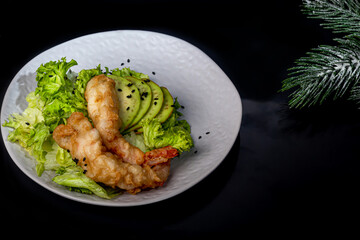 Avocado and king prawns salad on green leaves. Festive dinner New Years concept. Healthy eating. On a black reflective background.