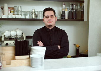 A young guy behind the bar looks at the camera