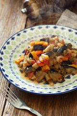 Vegetable stew in a flat plate on a wooden table