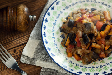 Vegetable stew in a flat plate on a wooden table
