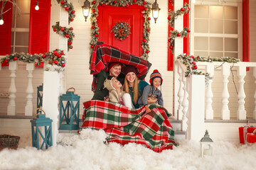 Young family with children at Christmas celebrates the new year together on porch of their house in winter