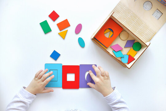 Learning colors and shapes. Children's wooden toy. The child collects a sorter. Educational logic toys for kid's. Children's hands close-up. Montessori Games for Child Development
