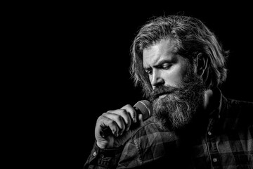 Male singing with a microphones. Bearded man in karaoke sings a song into a microphone. Male attends karaoke. Man with a beard holding a microphone and singing. Black and white