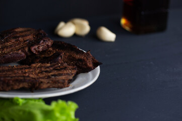 fresh grilled steaks, wild meat with spices on a black background, the concept of food with no GMOs