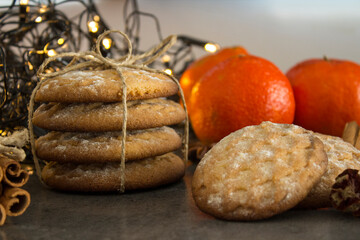 Christmas biscuits with festive decoration. Top view photo of homemade cookies, Christmas lights, tangerines, star anise and cinnamon sticks. 
