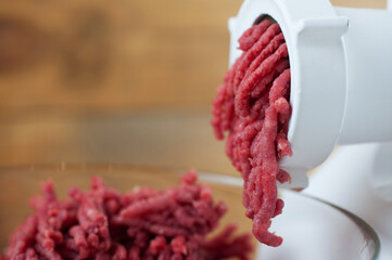 Cook makes minced fresh meat in a meat grinder