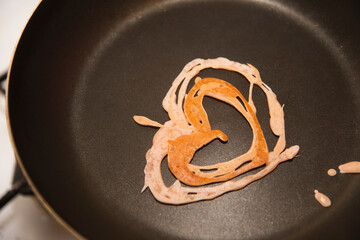 heart-shaped pancakes in a frying pan