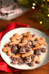 Plate of gingerbread man cookies with chocolate and anise balls. With red napkin In the background blurred light, candy sticks Christmas atmosphere. Copy Space