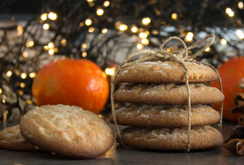Christmas biscuits with festive decoration. Top view photo of homemade cookies, Christmas lights, tangerines, star anise and cinnamon sticks. 
