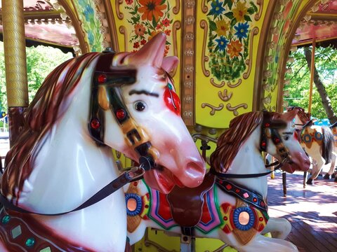 Children's carousels with plastic colored horses in the amusement Park. Warm spring day.