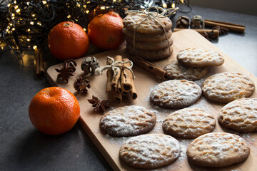 Christmas biscuits with festive decoration. Top view photo of homemade cookies, Christmas lights, tangerines, star anise and cinnamon sticks. 
