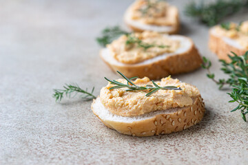 Homemade pate, spread or mousse in glass jar with sliced bread and herbs, light concrete background.