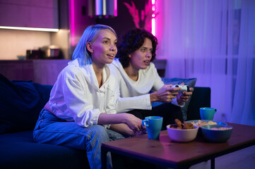 Handsome young man teaching how to play the video games to his girlfriend, on the couch, concept about home entertainment, video games.