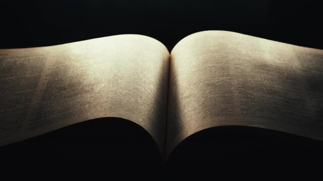 Dramatic  page turn in open illuminated book in dark room