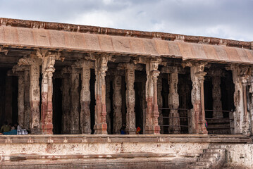 Hampi, Karnataka, India - November 4, 2013: Virupaksha Temple complex. Columned side of courtyard in front of Shiva sanctum is brownm rusty stone and offers shade for visitors.