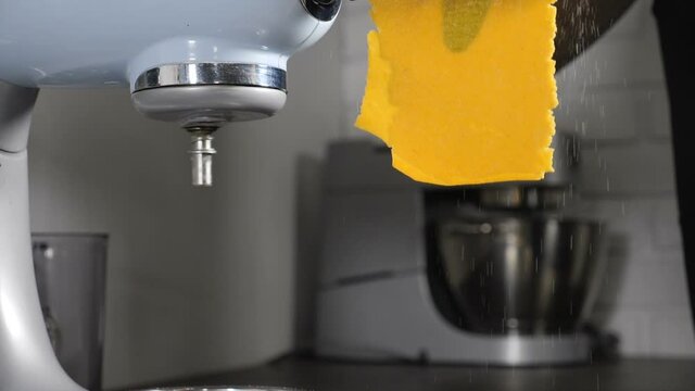 Chef making homemade pasta with turmeric and spinage leaves inside on professional equipment pasta machine. Traditional italian food, high cuisine restaurant. Rolling dough. Full hd