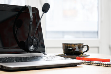 laptop with headphones, notebook with pen and cup of coffee on the table close-up