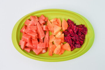 Top view of watermelons, papayas and dragon fruits assortment on a green plate.  Tropical fruits on a white background. 