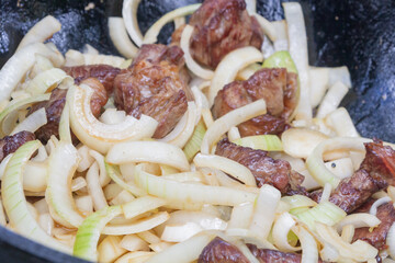 Cooking pilaf in a cauldron on the grill outside in the summer