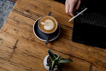 Cup of hot Cappuccino coffee on wooden table at cafe. with Cake Fresh invigorating drink with camera
