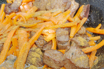 Cooking pilaf in a cauldron on the grill outside in the summer