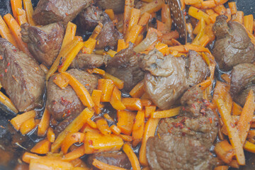 Cooking pilaf in a cauldron on the grill outside in the summer
