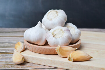 Fresh garlic on wooden plate isolated on black background. Selective focus.