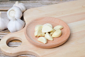 Fresh garlic on wooden plate isolated on wooden background. Selective focus.
